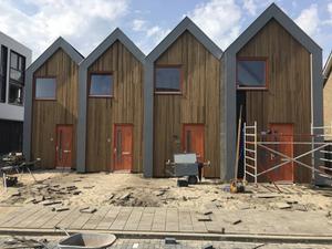 De voorgevels van de compacte microwoningen zijn bekleed met hout. De gezamenlijke tuin moet nog aangelegd. beeld Living First