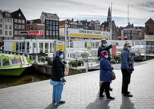 In een uitgestorven Amsterdam lopen toeristen met mondkapjes. beeld ANP, Robin van Lonkhuijsen