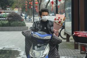 Valentijnsrozen kopen met een mondkapje op, in Hangzhou, China. beeld AFP