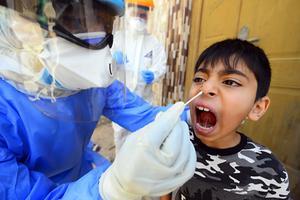 Een Irakese jongen wordt getest op het coronavirus. beeld AFP