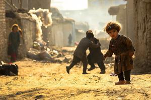 Afghaans kind poseert voor een foto buiten een tijdelijk opvangcentrum ter gelegenheid van Wereldkinderdag in Kabul, Afghanistan. beeld EPA, HEDAYATULLAH AMID